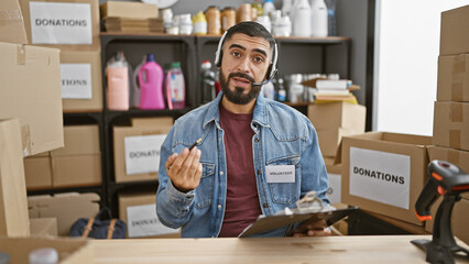 Handsome man with beard wearing headset as a volunteer in a donation center surrounded by boxes