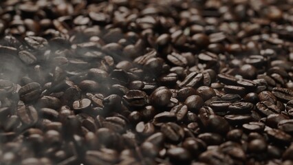 Close up of fresh brown coffee bean with roasted smoke from pile of coffee beans. Macrography of...