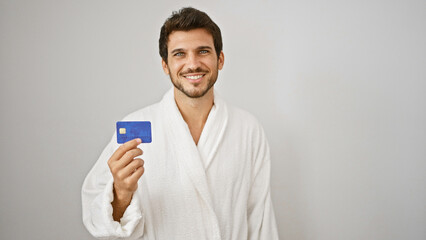 Handsome hispanic man in white robe showing credit card with smile on isolated background.