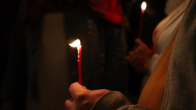 Holding burning candles in the church on Easter night.