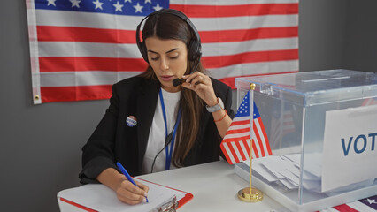 A focused hispanic woman working at an american voting center, with a ballot box and flag.