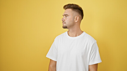 Handsome hispanic man with beard posing in white shirt against yellow wall, showcasing modern...