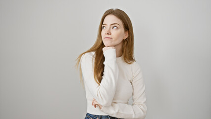 Thoughtful young caucasian woman in casual attire posing against a white background, embodying...