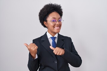 Beautiful african woman with curly hair wearing business jacket and glasses pointing to the back...