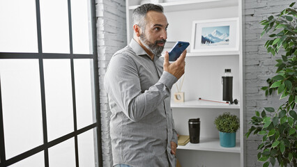 Mature bearded man using smartphone in modern office, professional, communication, technology, business