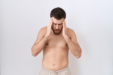 Fototapeta premium Young hispanic man standing shirtless over white background with hand on head for pain in head because stress. suffering migraine.
