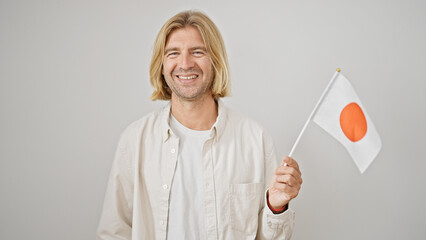 Handsome blond man holding a japanese flag against a white background, portraying a casual,...