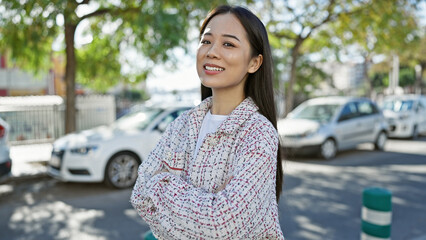 A young asian woman in a stylish tweed jacket poses confidently outdoors in a vibrant city...