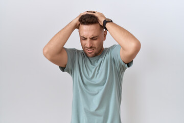 Hispanic man with beard standing over white background suffering from headache desperate and...