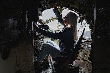 A blonde girl at the helm inside a military decommissioned An-12 cargo plane. Close up.