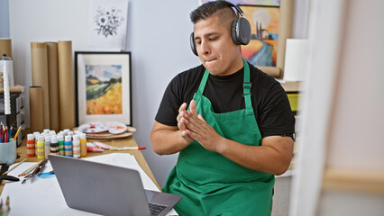 Handsome young latin man artist immersed in music, passionately dancing and painting at his art...