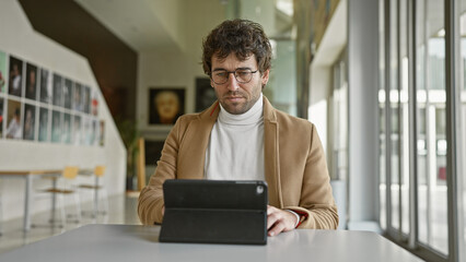 Hispanic man with beard working on tablet in modern office