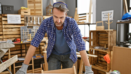 A middle-aged hispanic man with a beard works attentively in a carpentry workshop, embodying...