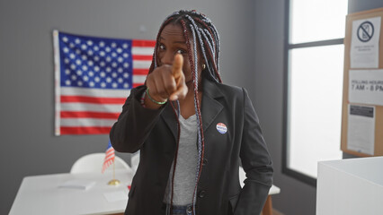 A confident african american woman with braids pointing at the camera in a college voting center...