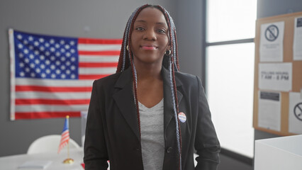 Confident african american woman with braids wearing an 'i voted' sticker in a room with american...