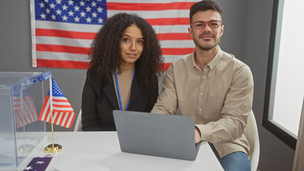 A man and a woman sit in an interior with a usa flag, symbolizing a political electoral context.