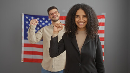 A woman and a man stand in an office with a us flag, portraying teamwork and leadership in a corporate american setting.