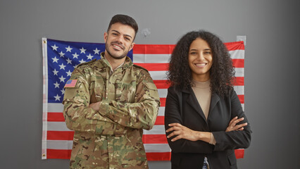 American soldier and businesswoman stand confidently in an office with the us flag.
