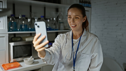 Smiling woman scientist in lab coat taking selfie in modern laboratory