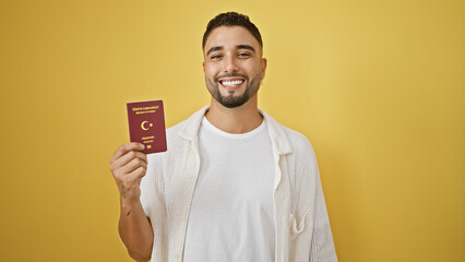 Smiling young man holding turkish passport against yellow background, depicting travel readiness