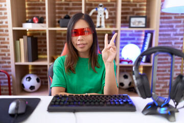 Middle age chinese woman wearing virtual reality glasses smiling with happy face winking at the...