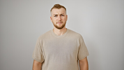 Fototapeta premium Angry young caucasian man with beard in casual shirt on white background looking displeased.