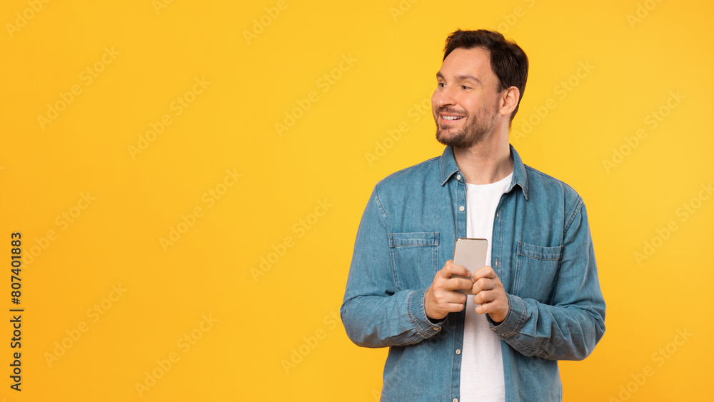 Poster a man wearing a blue shirt is seen holding a cell phone. he appears to be engaged with the device, p