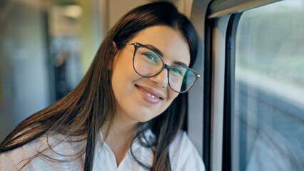 Young beautiful hispanic woman smiling happy leaning on the window inside train wagon