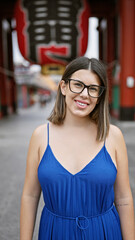 Fototapeta premium Beautiful hispanic woman donning glasses, flashing a cheerful smile at the senso-ji temple, immersed in japanese tradition, joyful latin adult exploring the rich culture of tokyo