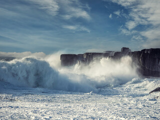 Powerful tall ocean wave hit stone cliff and create huge splash of water. County Clare, Ireland....