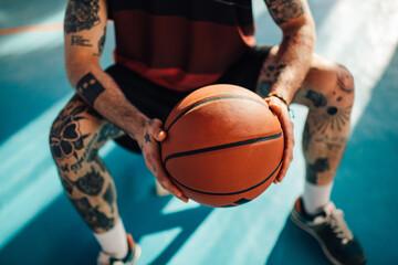 Unrecognizable tattooed male basketball player with a ball in his hands
