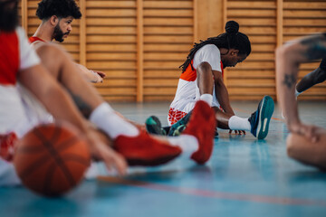 Muslim african man basketball player stretching his legs in a sports hall