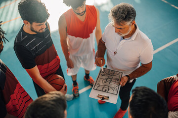 High angle view of a mature coach discussing game tactics with his diverse team