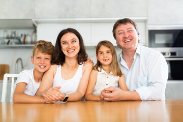 Fototapeta premium Joyful family with two children posing at dinner table in kitchen at home