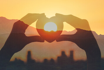 Hand shape heart in the city at sunrise 