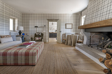 A living room in a country house with a large fireplace and oak wood stacked on the hearth