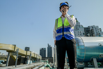 A young engineer checks equipment on a rooftop amidst urban skyline, clipboard in hand, ensuring...