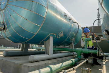 Engineer in safety gear conducts inspection on large industrial water tanks on a building rooftop....