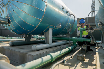 Engineer in safety gear conducts inspection on large industrial water tanks on a building rooftop....