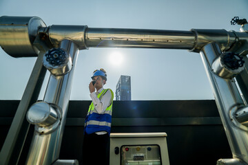 Engineer in safety gear conducts inspection on large industrial water tanks on a building rooftop....