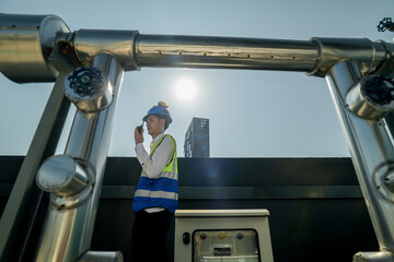 Engineer in safety gear conducts inspection on large industrial water tanks on a building rooftop....