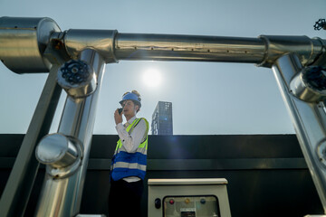 Engineer in safety gear conducts inspection on large industrial water tanks on a building rooftop....