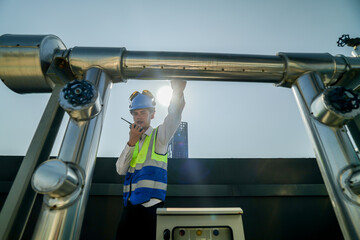 Urban rooftop scene showing a young engineer with a radio, inspecting and adjusting equipment in a...