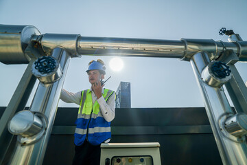 Engineer in safety gear conducts inspection on large industrial water tanks on a building rooftop....