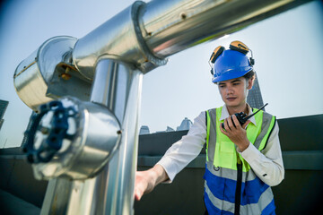 Engineer in safety gear conducts inspection on large industrial water tanks on a building rooftop....