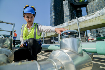 engineer inspecting HVAC equipment with a tablet on a building rooftop. An engineer attentively...