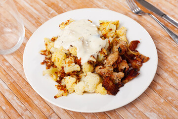 Plate of delicious boiled cauliflower with fried lard and sauce