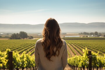 woman with long hair overlooking vineyard landscape