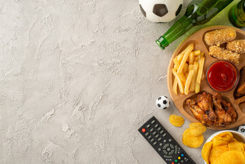 A high angle view of a table set with snacks, including chicken wings, fries, chips, and beer, perfect for watching a football game