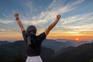 Winning success young woman with arm flexed facing the sunset.